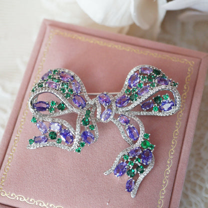Elegant RosyCozy bow-shaped brooch featuring sparkling purple and green zircons