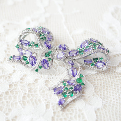 Elegant RosyCozy bow-shaped brooch featuring sparkling purple and green zircons
