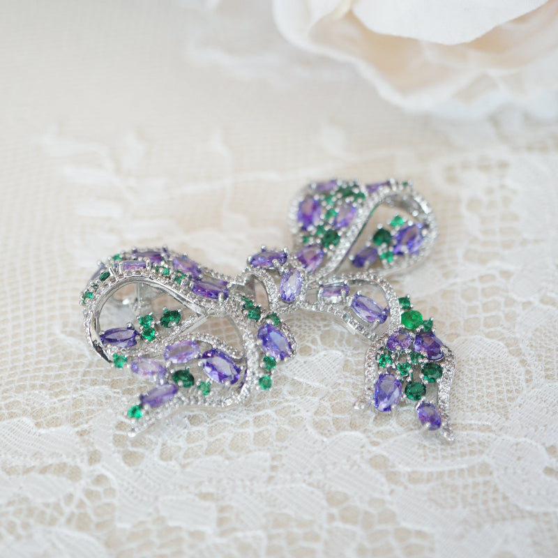 Elegant RosyCozy bow-shaped brooch featuring sparkling purple and green zircons