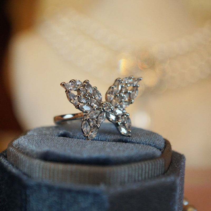 Elegant butterfly ring crafted with marquise and round-cut clear zircons set in an 18K white gold plated band, displayed on a blue velvet ring box