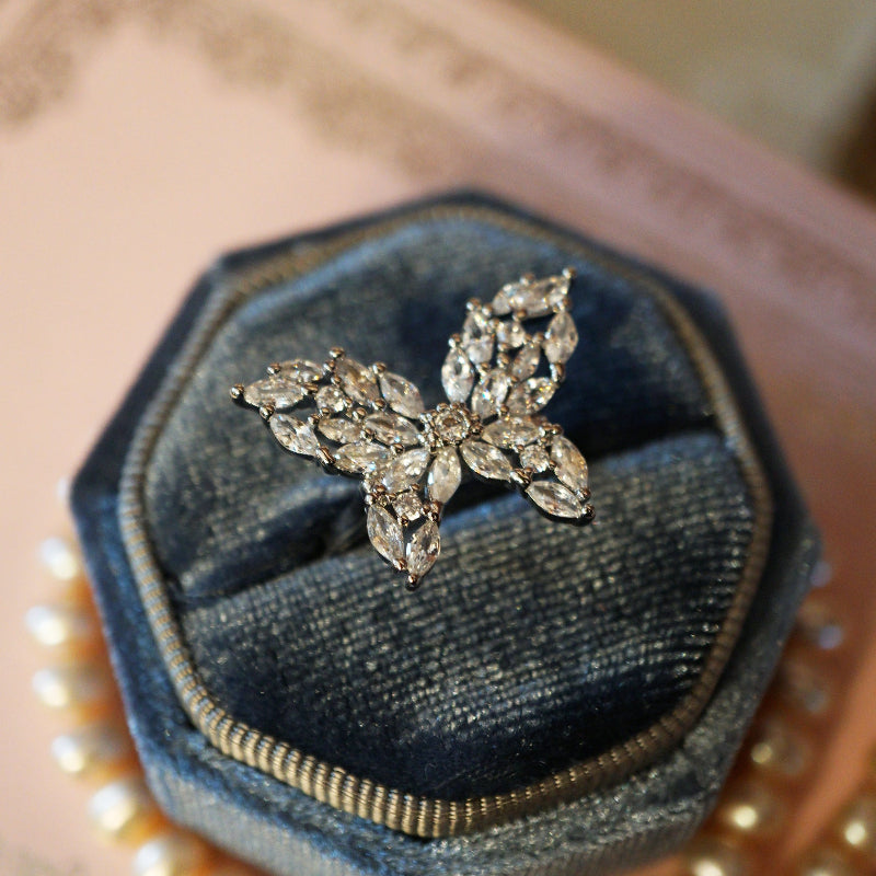Elegant butterfly ring crafted with marquise and round-cut clear zircons set in an 18K white gold plated band, displayed on a blue velvet ring box